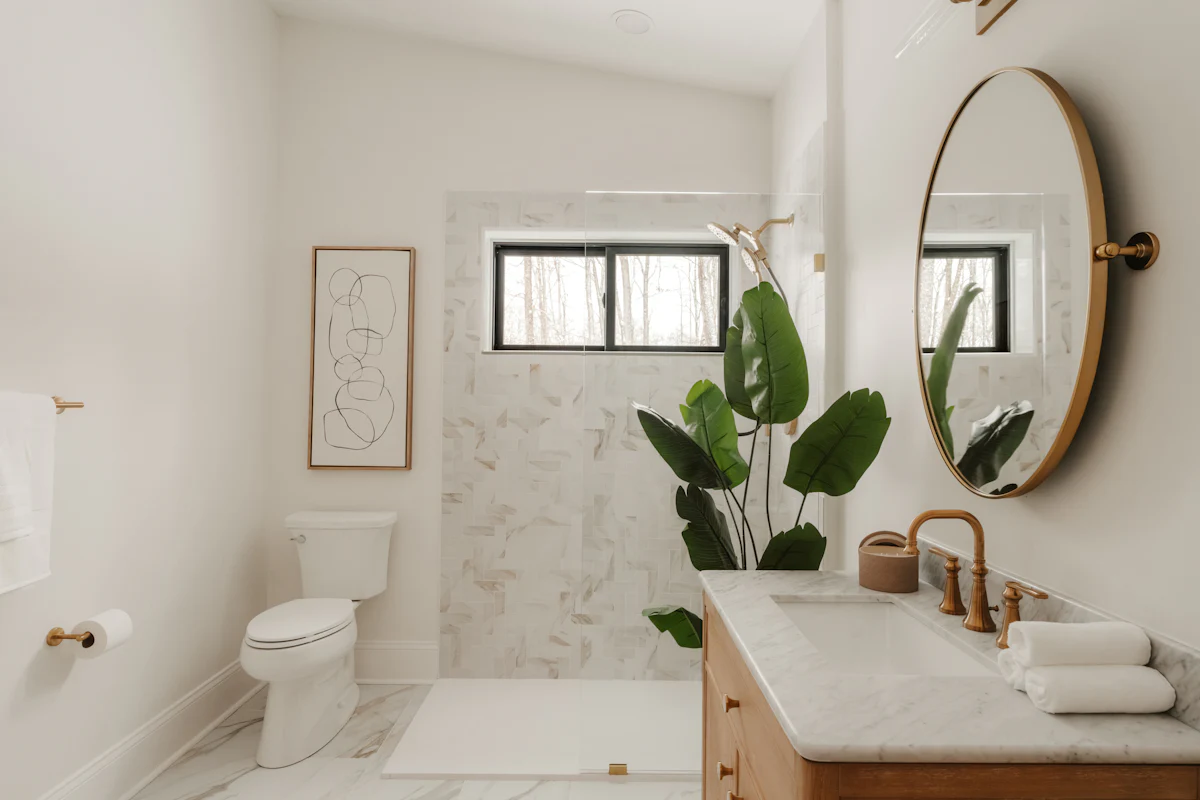 A bathroom with marble surfaces, warm wood cabinetry and a freestanding tub