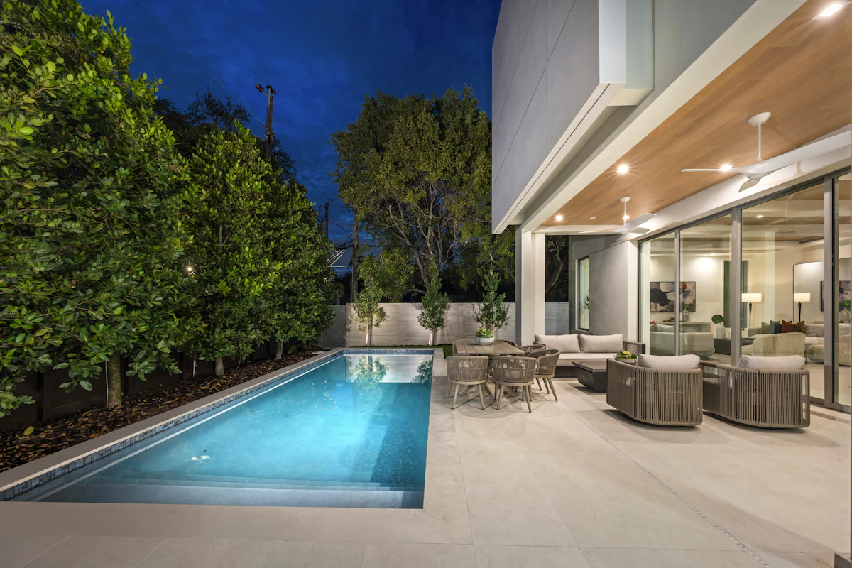 A pool bordered by stone decking, outdoor seating and mature planting