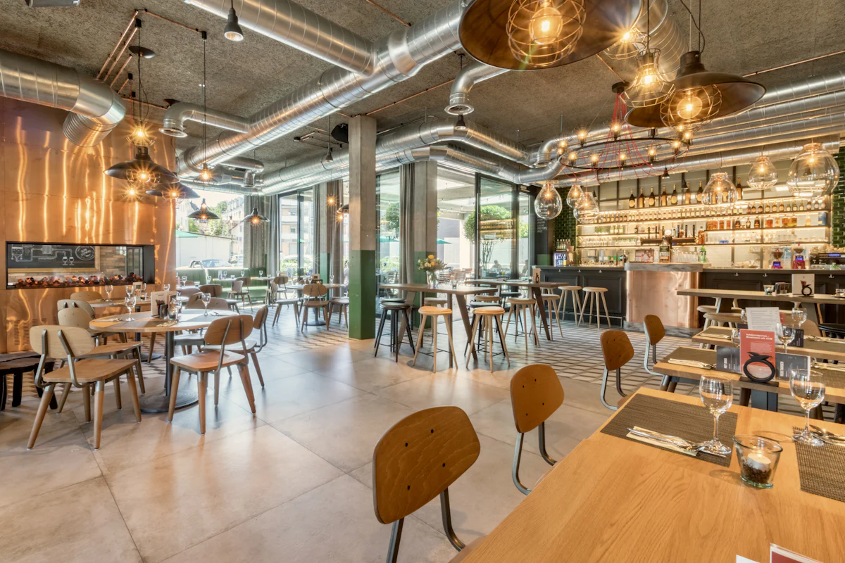 A daylit restaurant dining room with wood tables and an open ceiling